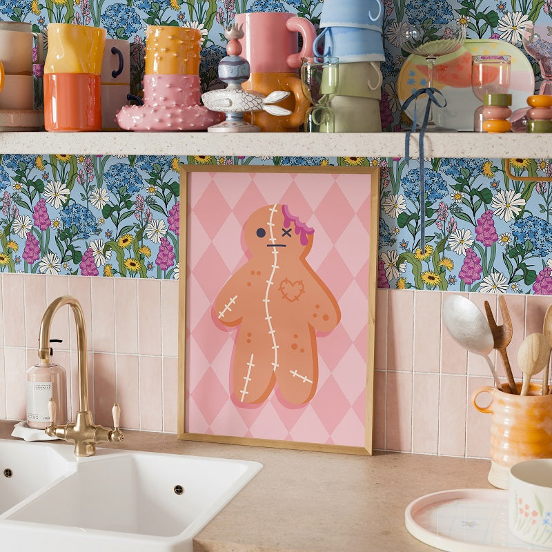 Kitchen counter with colorful mugs, a gingerbread man poster, and floral wallpaper.