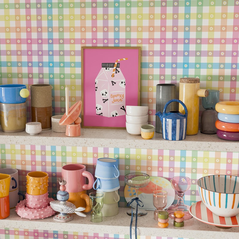 Colorful kitchenware on a shelf against a checkered wall with a pink milk carton picture.