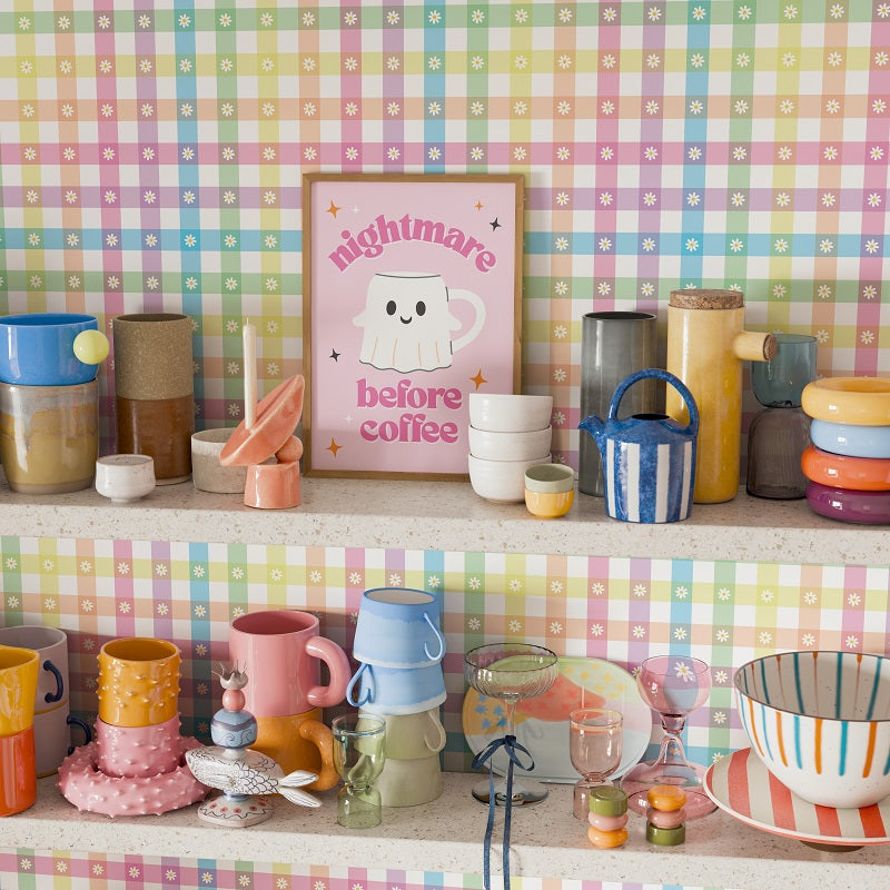Colorful kitchenware on a shelf with a checkered patterned wall.