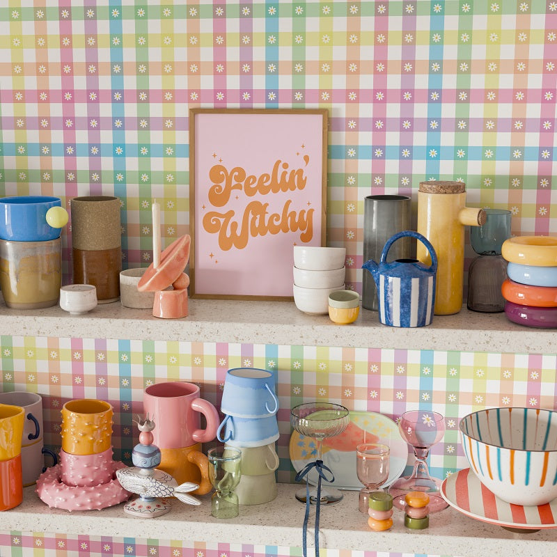 Colorful kitchenware on a shelf with a 'Feelin' Witchy' sign against a checkered wall.