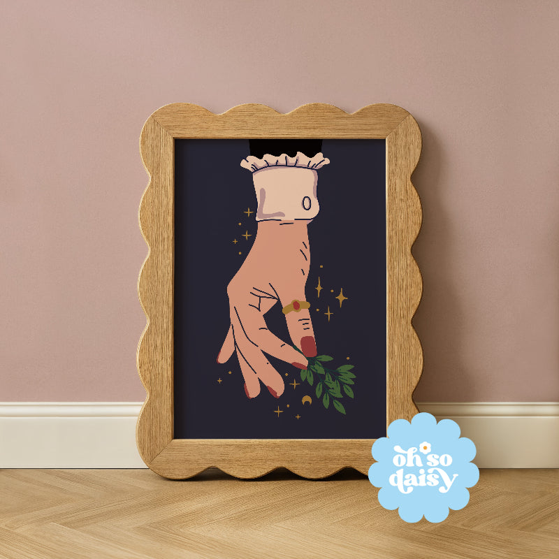 Framed artwork of a hand holding a flower with 'oh so daisy' logo on a wooden floor.