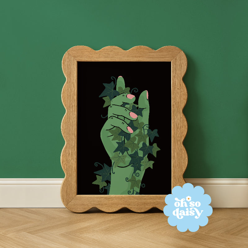 Framed artwork of a green hand holding flowers against a black background, with 'oh so daisy' logo on a green wall.