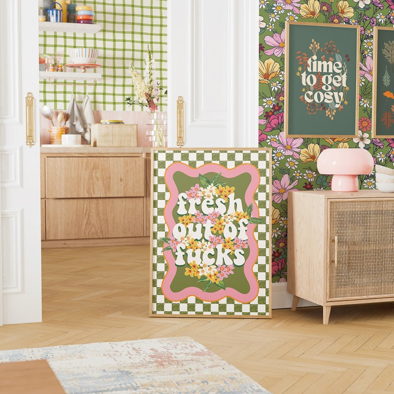 a colorful and vibrant interior with a checkered pattern on the walls and a wooden cabinet. There is a large sign with the text "fresh out ofucks" in the center of the room, surrounded by various decorative elements such as flowers, vases, and other home decor items.
