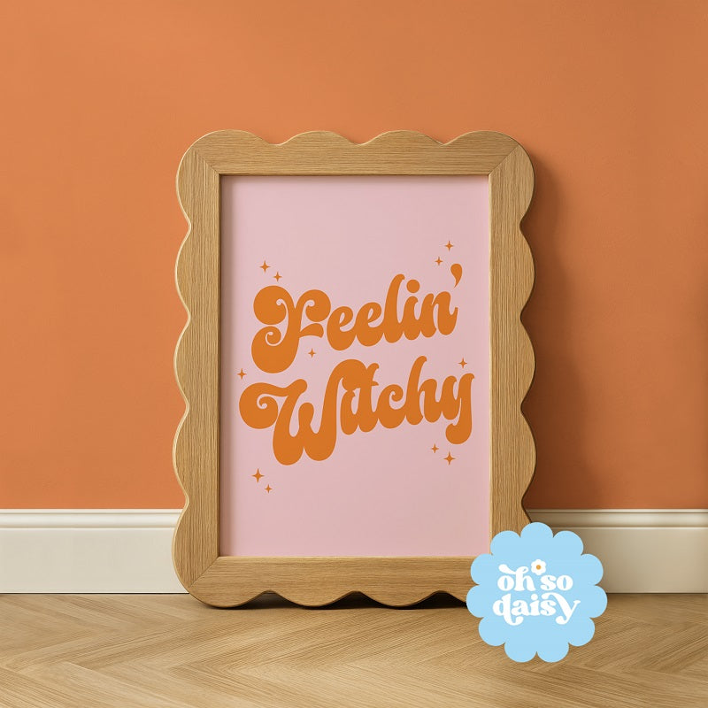 Wooden-framed artwork with 'Peelin' Witchy' text on a pink background, against an orange wall.