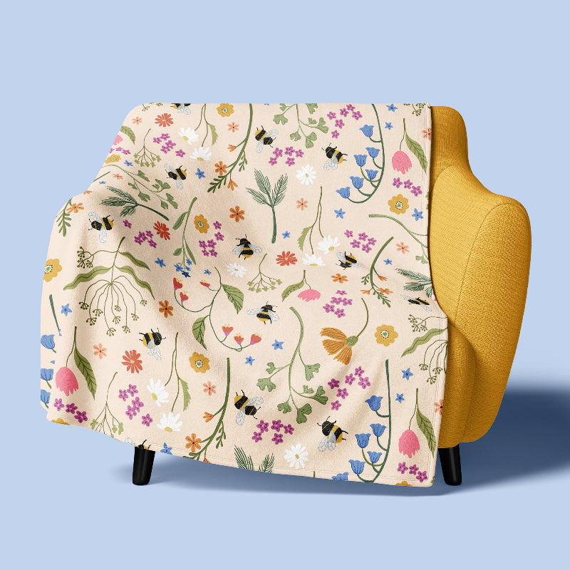 Floral patterned throw blanket draped over a yellow armchair on a light blue background
