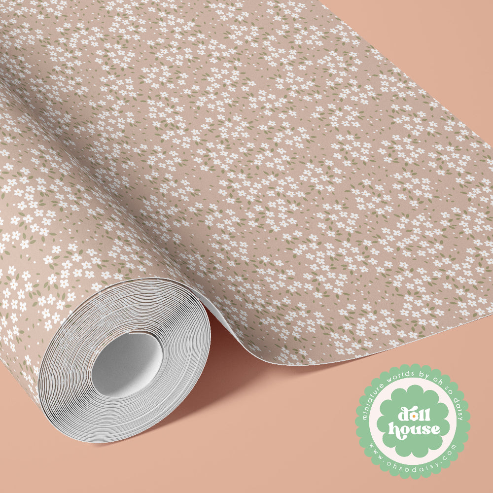 A roll of floral-patterned wallpaper or fabric shown partially unrolled on a peach background. The design features small white flowers with green centers on a warm beige base.