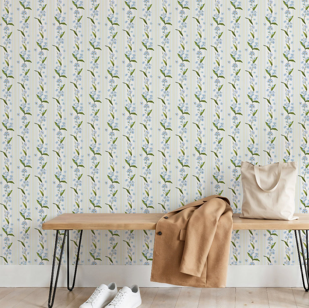 Myosotis Stripe wallpaper featuring delicate forget-me-not flowers with soft vertical stripes in a light, airy bedroom setting