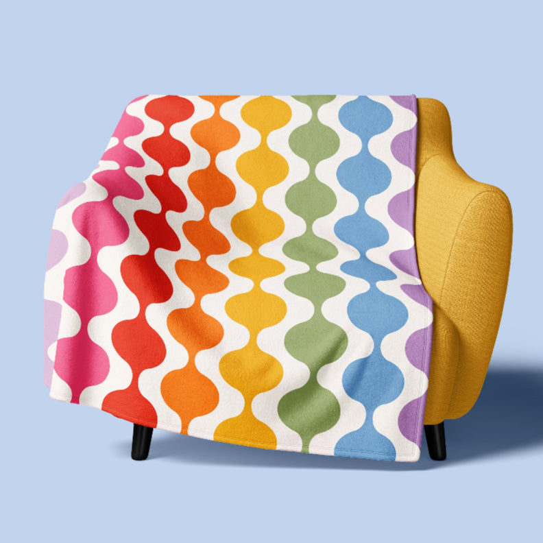 Colorful patterned blanket draped over a chair against a light blue background