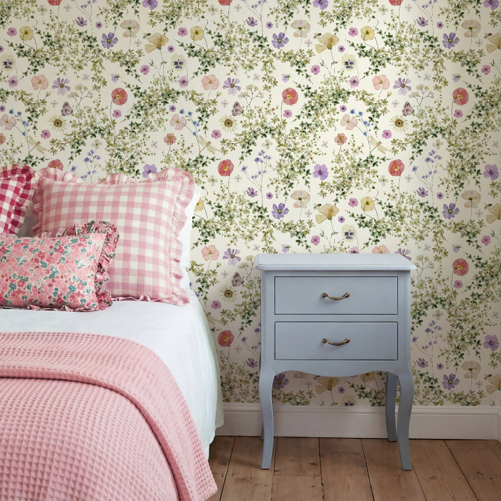 Secret Garden floral wallpaper in a soft country bedroom with neutral bedding and vintage wooden furniture, creating a calm English cottage style interior