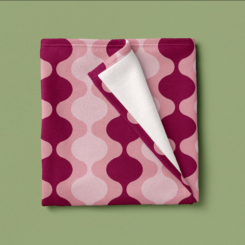 Folded blanket with pink and purple geometric pattern on a green background