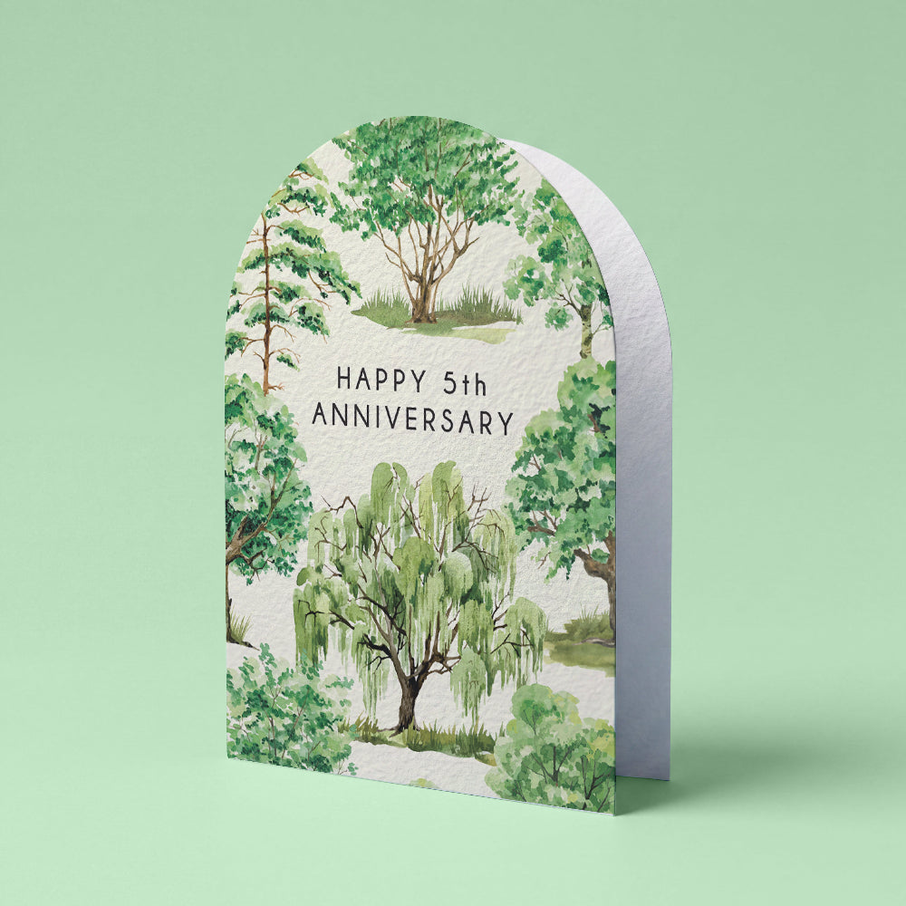An arched anniversary card featuring a watercolor garden illustration with the text 'HAPPY 5th ANNIVERSARY' in black serif font, shown standing upright against a light mint green background.