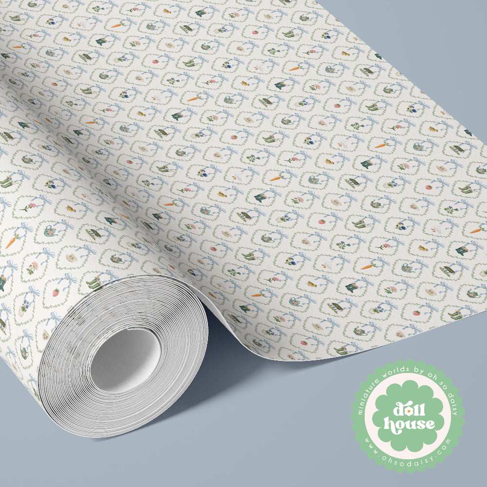 A roll of patterned wallpaper or wrapping paper shown partially unrolled on a light blue-gray background. The paper has a white base with a repeating small motif in muted blue, green, orange, and beige tones.