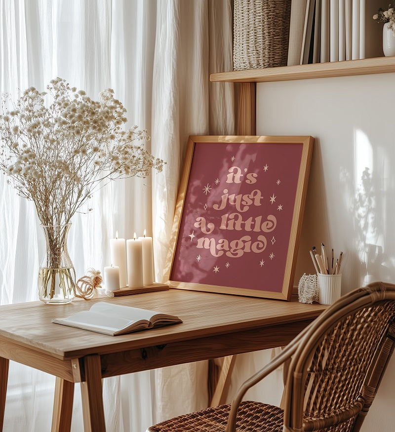 Wooden desk with a framed print, candles, and books in a cozy room.